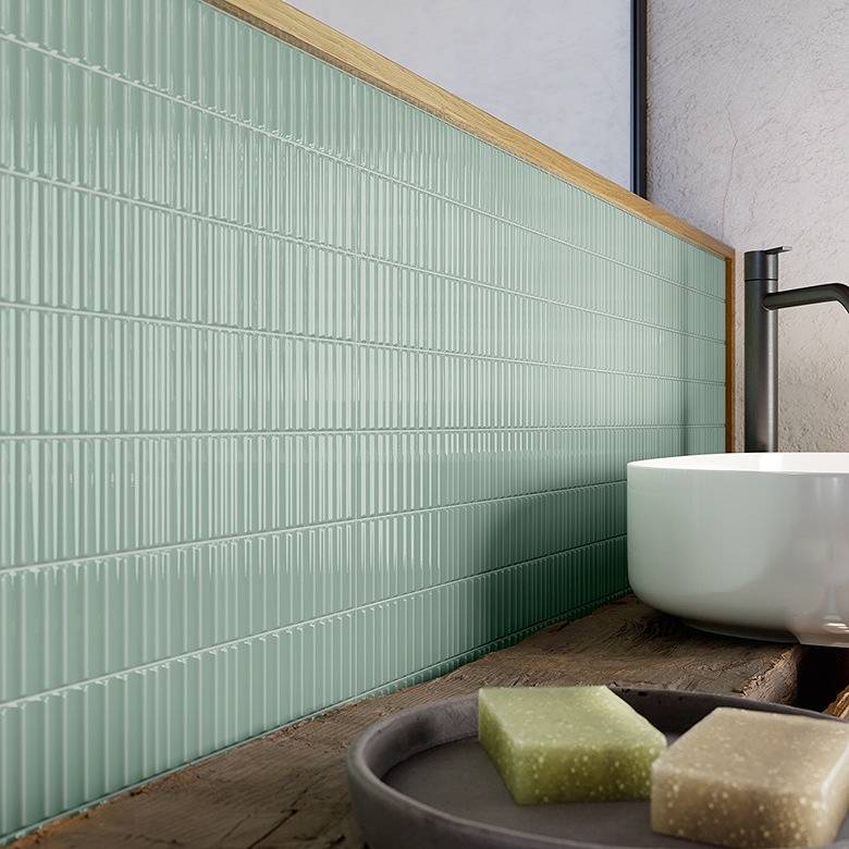 Mint green fluted tiles used as a half-height bathroom wall behind a countertop basin with wooden trim