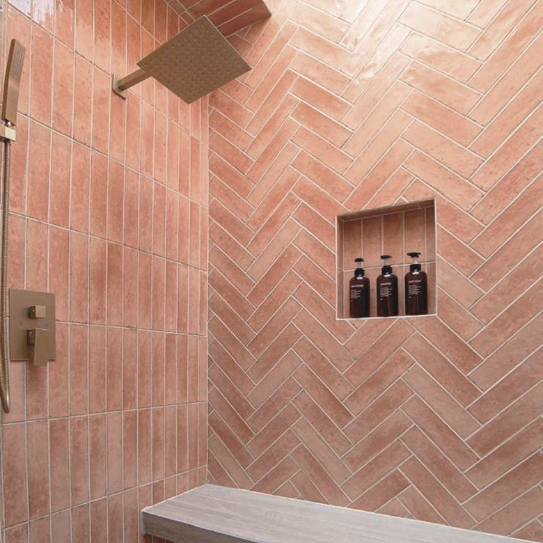 Pink metro tiles laid vertically and in a herringbone pattern across shower walls with a built-in tiled niche