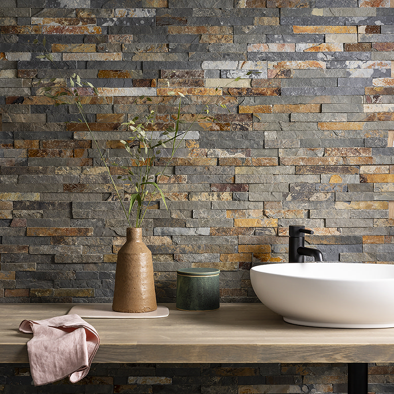 Bathroom basin with a textured natural stone split-face tile feature wall in grey, brown and rust tones
