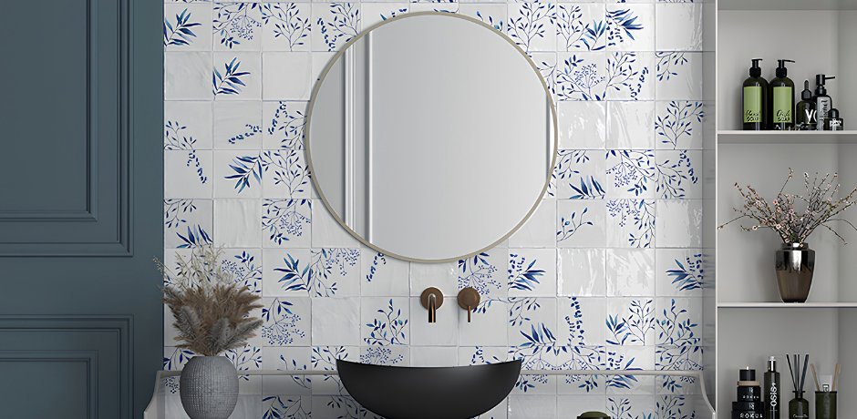 Blue and white floral bathroom wall tiles creating a decorative feature behind a black basin and round mirror