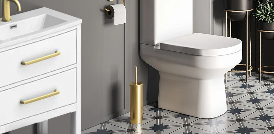 white toilet with patterned tiles and brass toilet brush