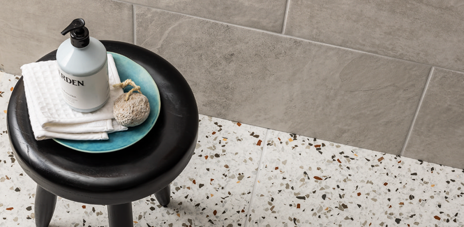 terrazzo tiles with light grout and a dark bathroom stool