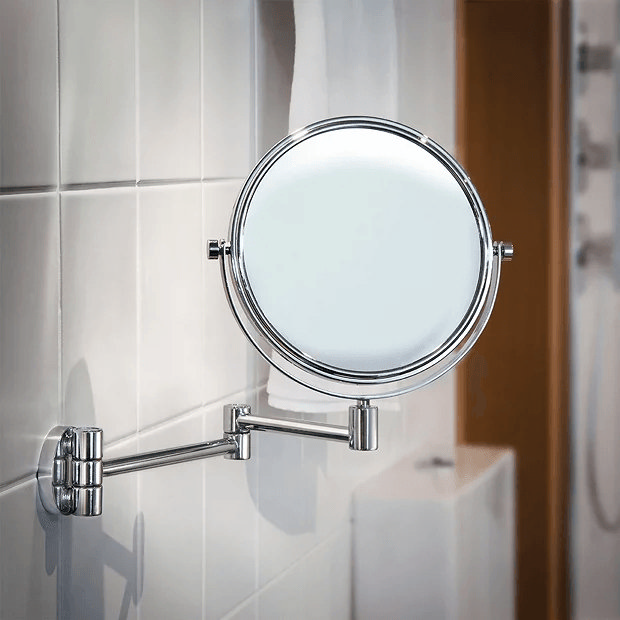 Wall mounted chrome shaving mirror on white tiles 