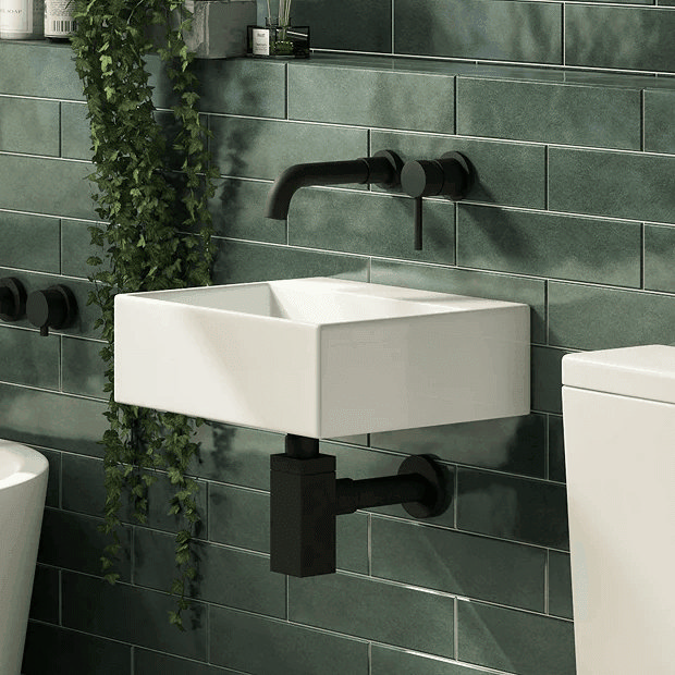 Black wall mount tap with wall mount basin on dark green tiles
