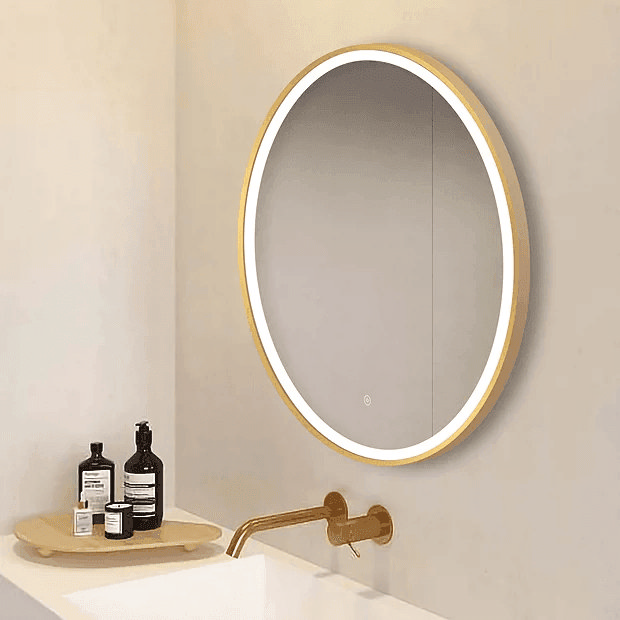 Round brass light up mirror on cream wall with brass wall mount tap
