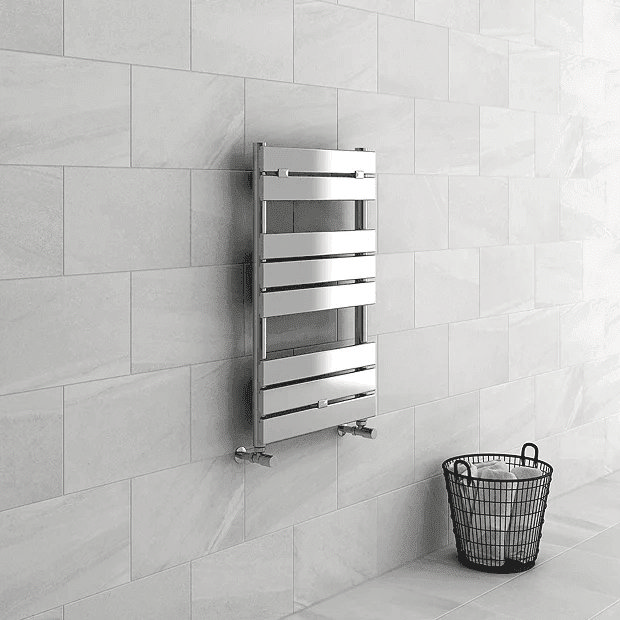 Chrome towel rail on grey tiles with black towel basket