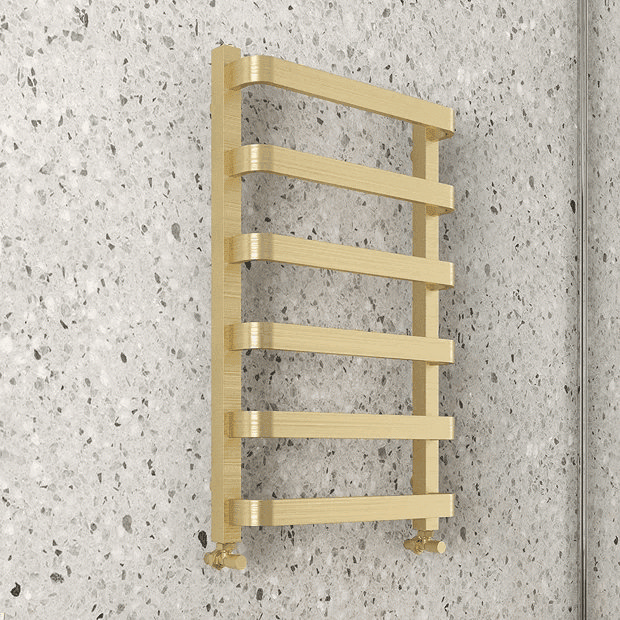 Brass heated towel rail on terrazzo wall
