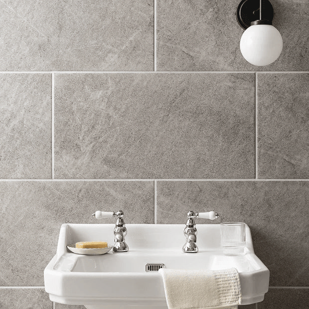 Grey stone tiles behind white basin with chrome taps