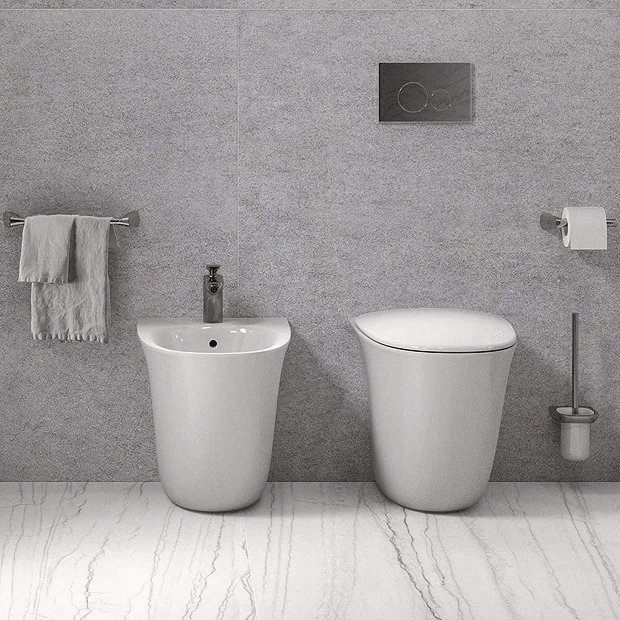 Modern toilet and bidet against grey wall