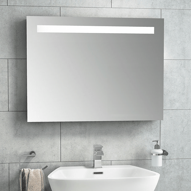 Wall mount illuminated mirror on white bathroom tiles