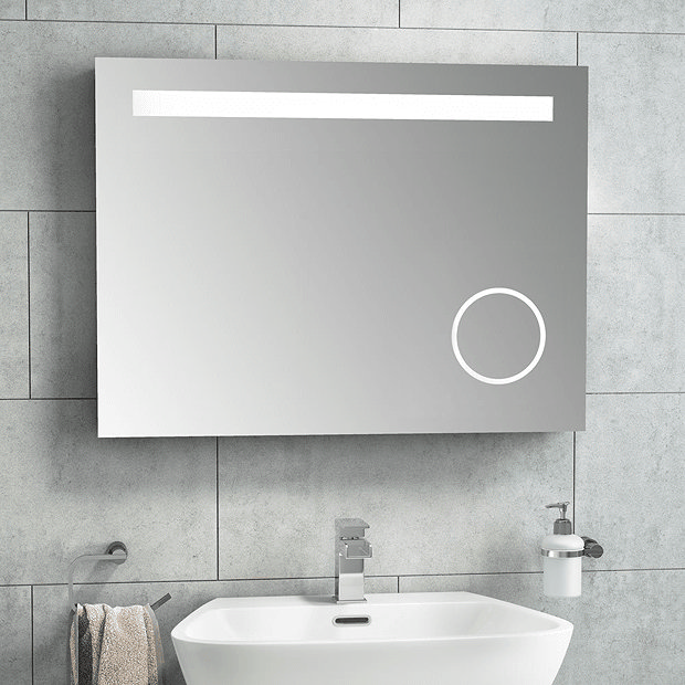 Fog free mirror on grey tiled wall with basin and chrome tap