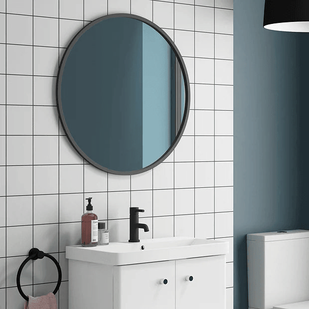 Black round mirror on white tiled wall