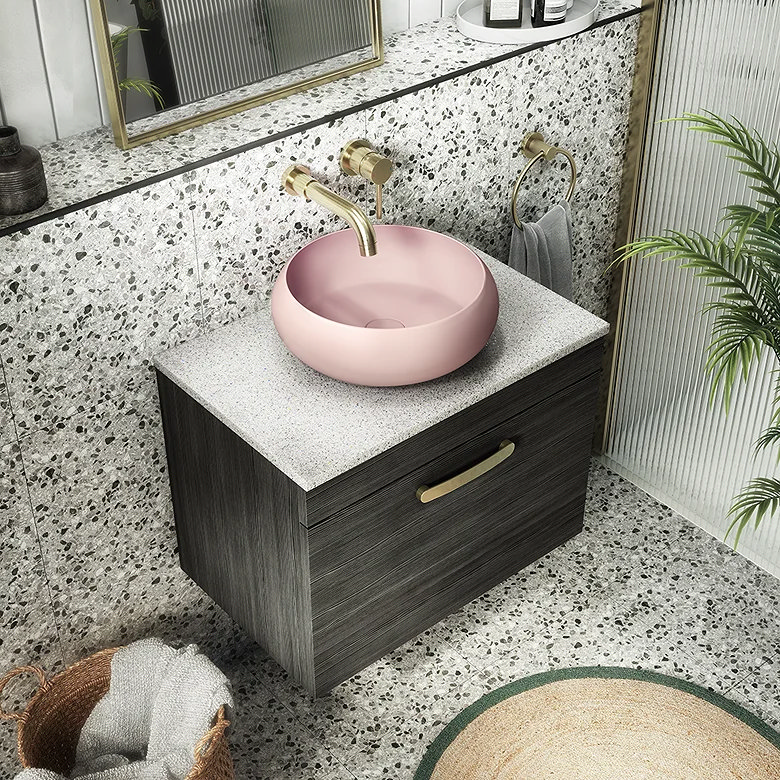 mid century modern bathroom vanity with terrazzo tiles, pink countertop basin and brushed brass wall mounted tap