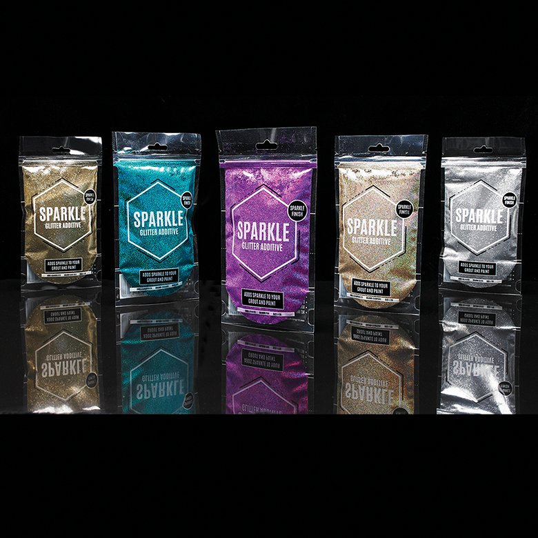 Five packets of Sparkle Glitter Additive in various colors, including gold, turquoise, purple, and silver, displayed on a reflective surface against a black background.