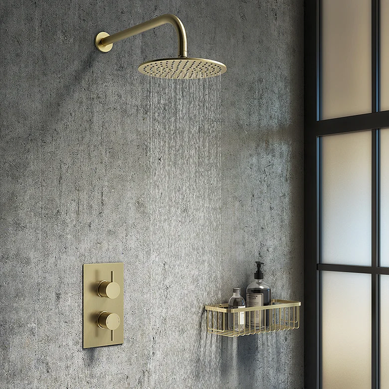 Wall-mounted brushed brass shower basket holding bottles of toiletries, set against a textured grey wall, adding a touch of elegance and functionality to the bathroom decor.
