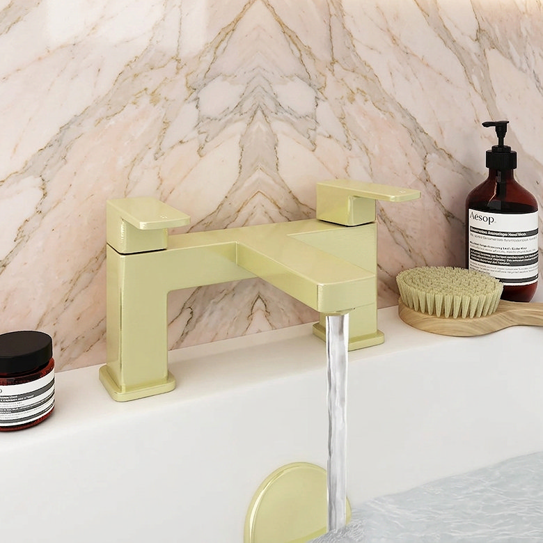 Modern yellow bath mixer tap with water flowing, set against a pastel pink hexagonal tile backdrop, accompanied by stylish bathroom essentials.