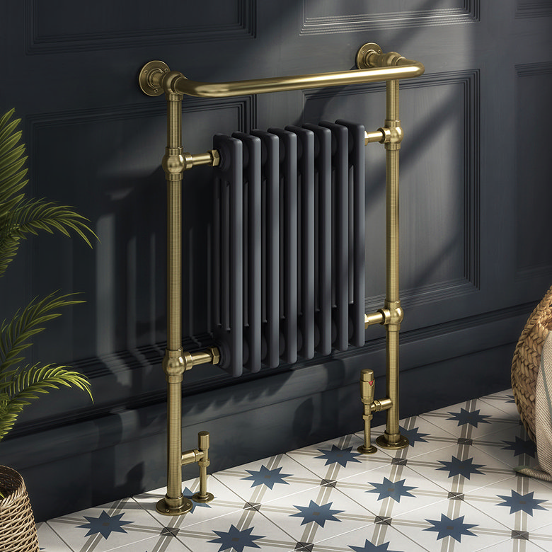 brass and anthracite grey heated towel radiator against grey painted wall and traditional patterned tile floor
