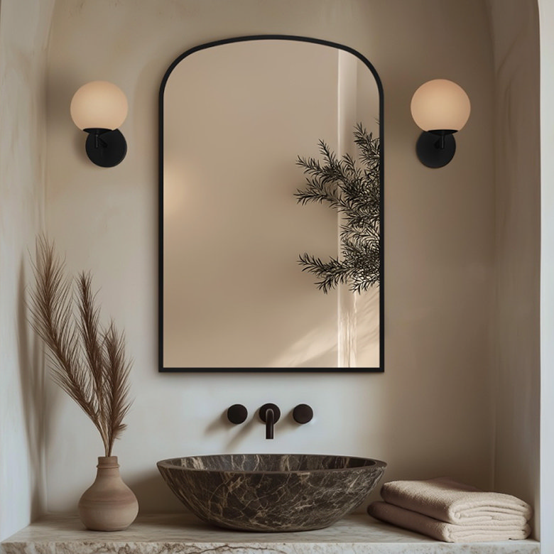 black arched mirror hung above countertop basin
