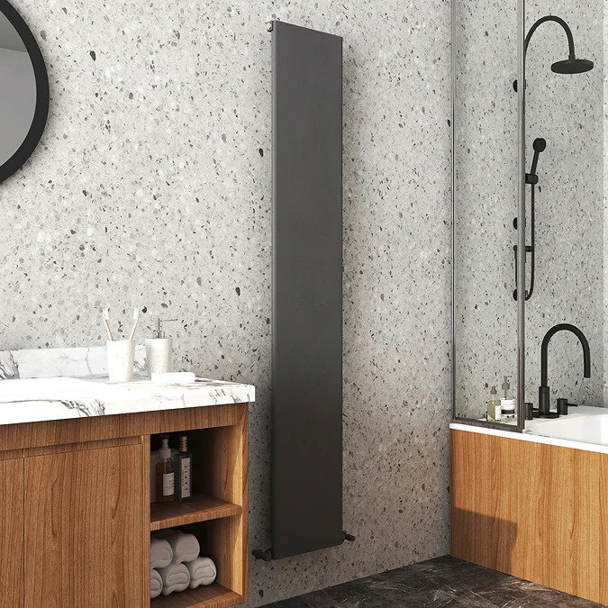 long anthracite solid radiator against light speckled stone wall