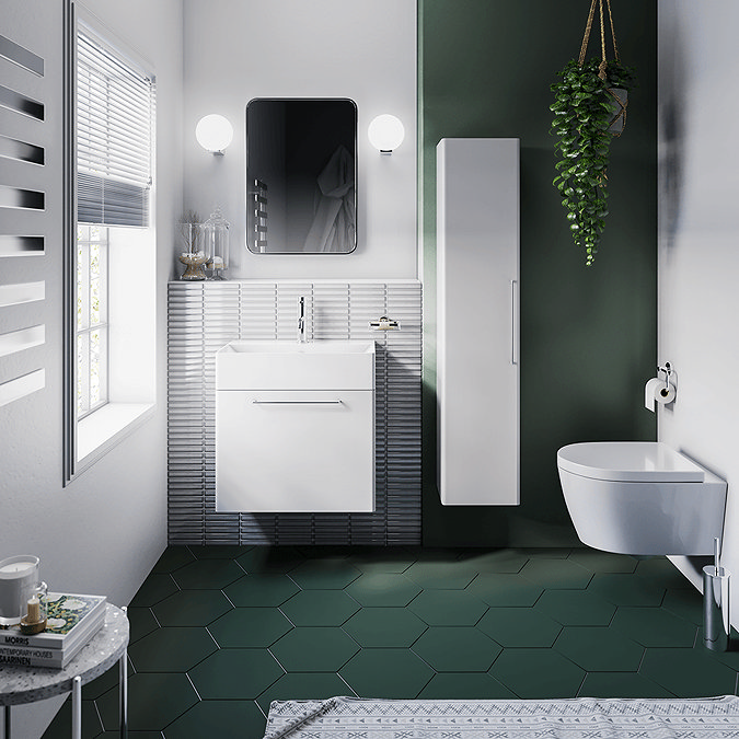 Small bathroom with white furniture and dark green walls and floor tiles