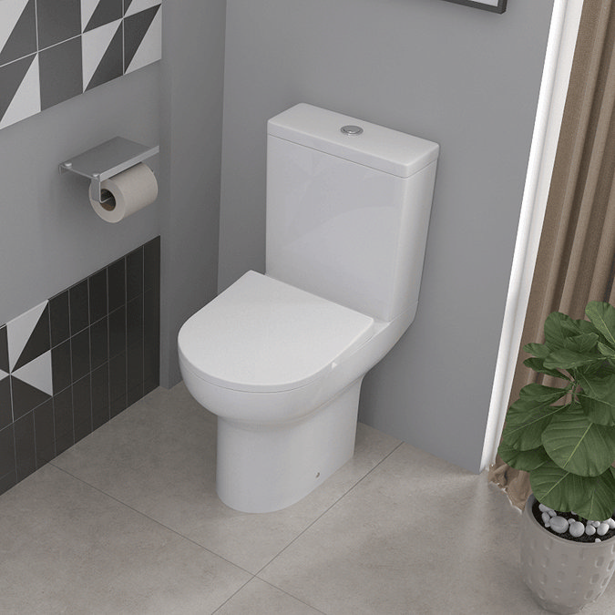 Modern compact toilet on large square tiles and small plant