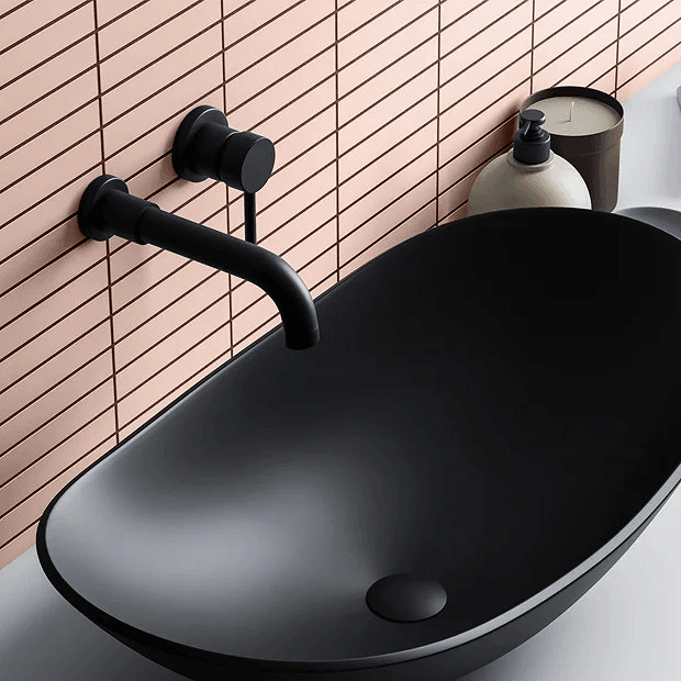 Pink tiles behind black basin with black tap