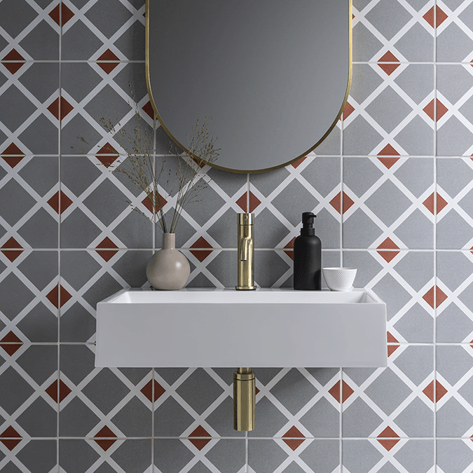 Brushed brass basin tap with grey and orange tiles
