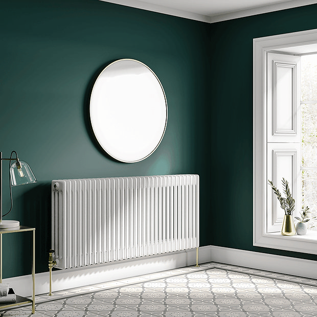 White radiator on green wall with round mirror