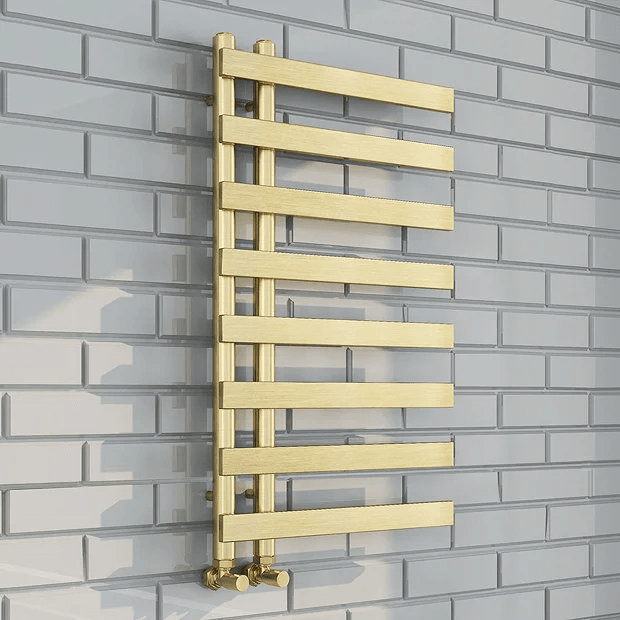Brass heated towel rail on white brick wall