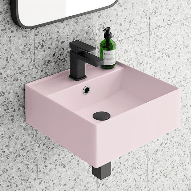 Pink wall mount basin with black taps and waste