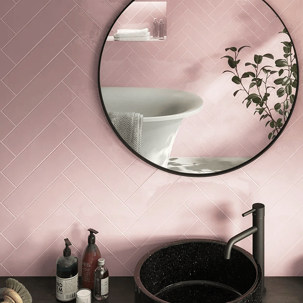 Pink tiles underneath black mirror over a black sink 