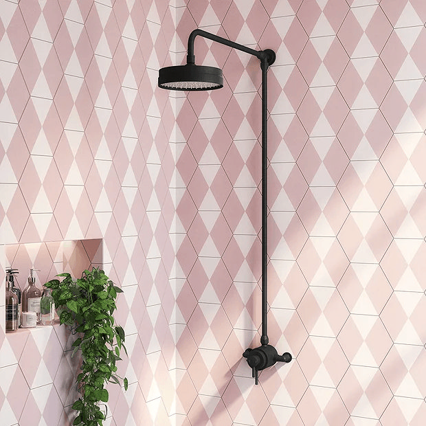 Pink and white tiles and black shower next to plant