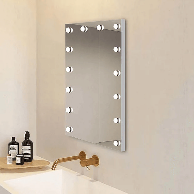 Light up mirror with light bulbs on cream wall with brass taps