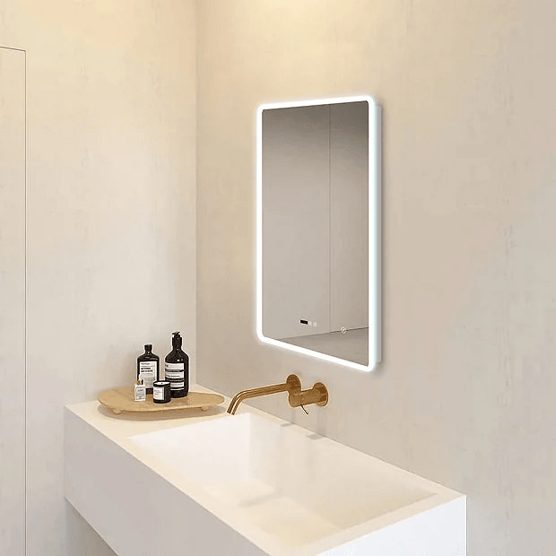 Illuminated mirror in cream bathroom with brass taps