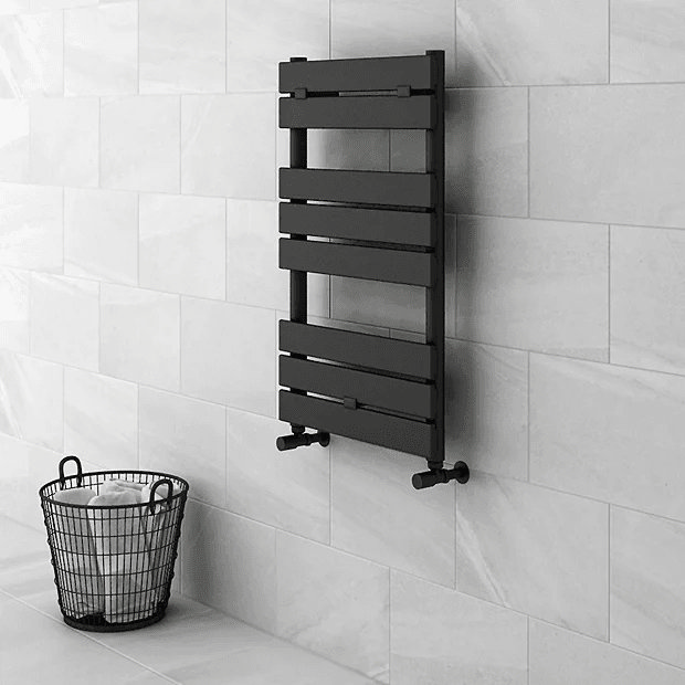Black heated towel rail on white tiled wall