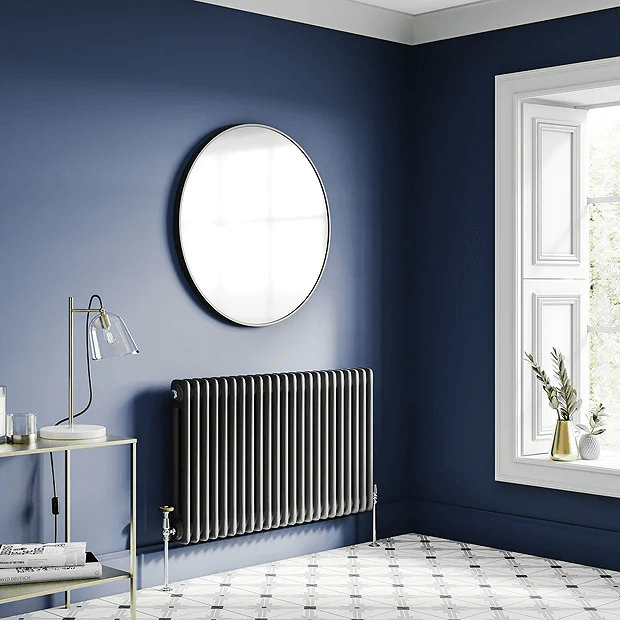 Black column radiator on navy blue wall with round mirror