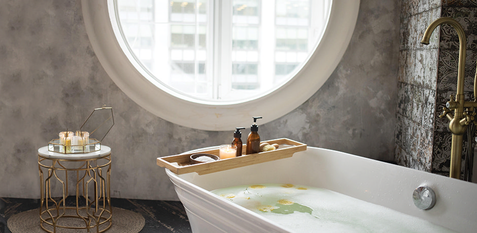 Large bath in front of round window in grey bathroom