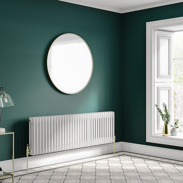 Traditional white horizontal column radiator mounted on a dark green wall beneath a round mirror