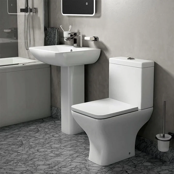 Toreno contemporary bathroom suite with square basin and pedestal, close-coupled toilet, and brushed chrome fittings, set against concrete-effect walls and a marble-patterned floor.
