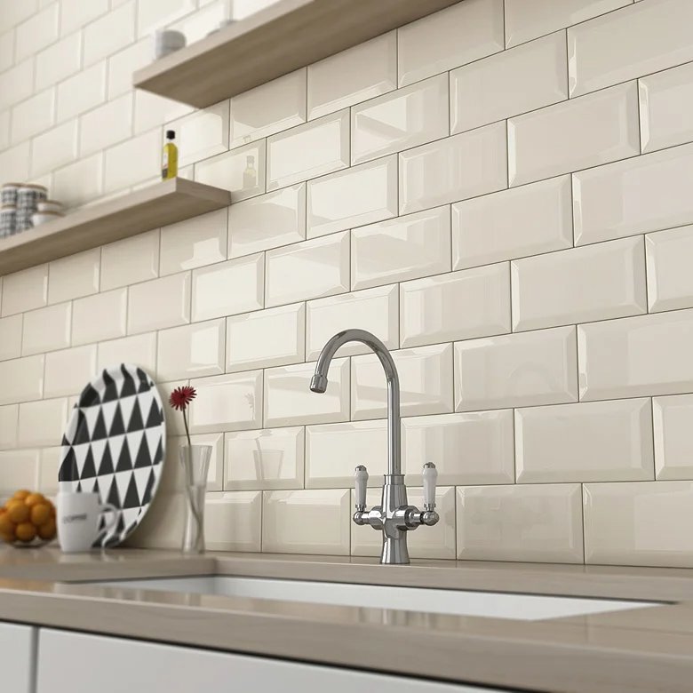 Warm cream gloss metro tiles with subtle bevel behind a kitchen sink.