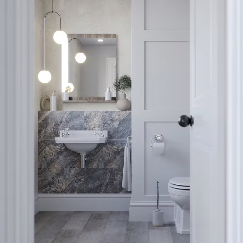 Compact bathroom featuring marble-effect tiles, elegant wall-hung sink, soft pendant lighting, and white wainscoting for a sophisticated, modern look.