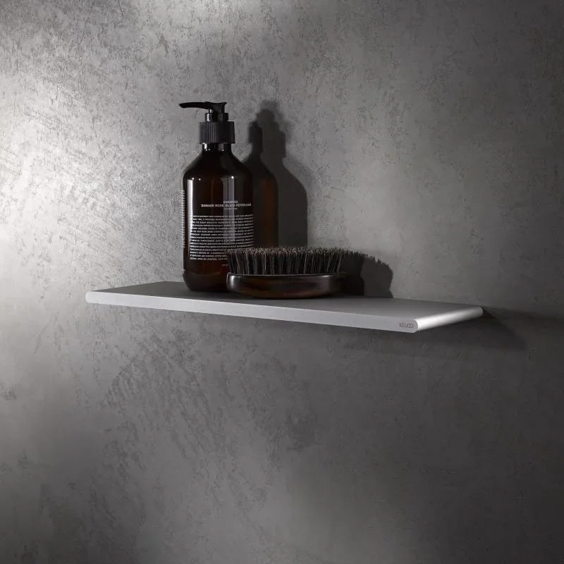 Minimalist floating shelf in a modern bathroom with a sleek grey wall, displaying grooming essentials like a brown soap dispenser and brush.