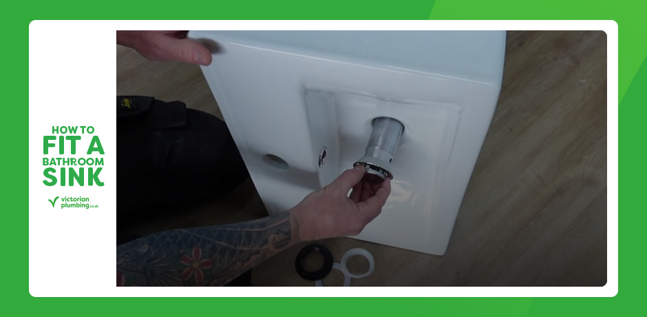 Fitting a click-clack waste into the underside of a bathroom sink before tightening the nut