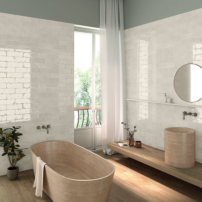 Luxurious bathroom featuring glossy white brick-effect wall tiles that reflect natural light, enhancing the bright and airy feel of the space.