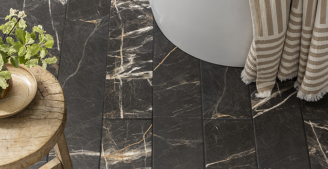 Luxurious black marble effect floor tiles in a bathroom, paired with a wooden stool and striped towel for a sophisticated look.