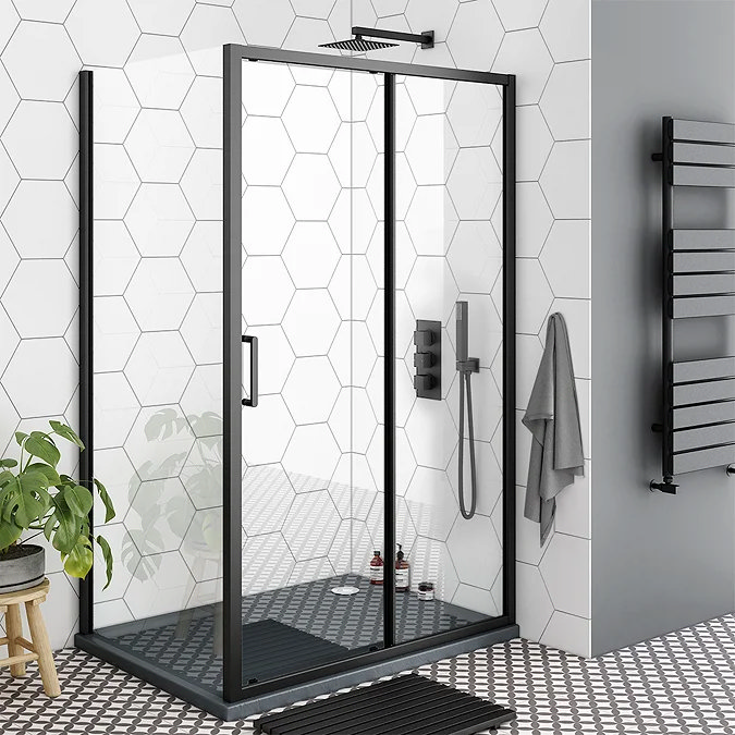 Toreno black-framed shower enclosure with sliding doors, set against white hexagonal tiles and monochrome flooring for a bold, modern bathroom look.