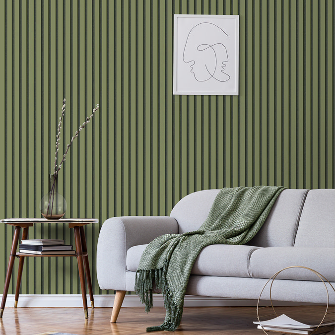  A stylish living room with green fluted wall panelling, a grey sofa draped with a matching green throw, and a small side table holding a vase and books, creating a modern, cosy atmosphere. A minimalist line-art frame decorates the wall above the sofa.