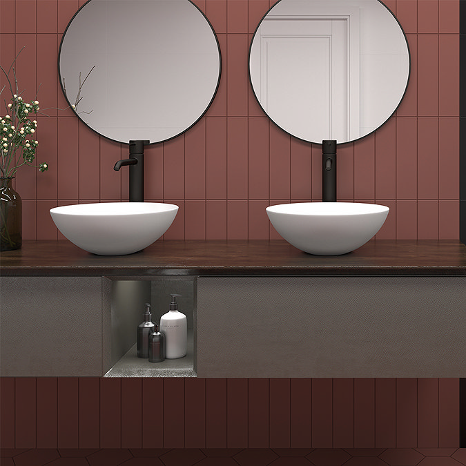 Modern bathroom with warm terracotta wall tiles, dual white vessel sinks, matte black taps, and a floating wood vanity featuring open shelving for storage.