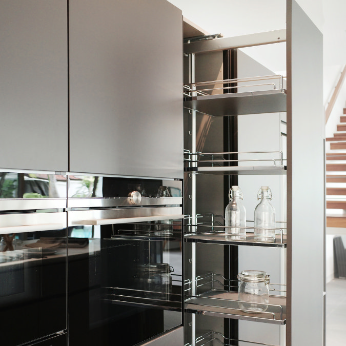 Modern pull-out pantry storage in sleek grey kitchen with chrome shelving and glass jars