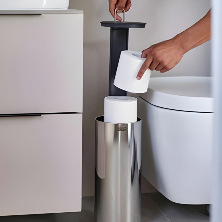 Modern freestanding toilet roll holder with hidden storage next to wall-mounted toilet